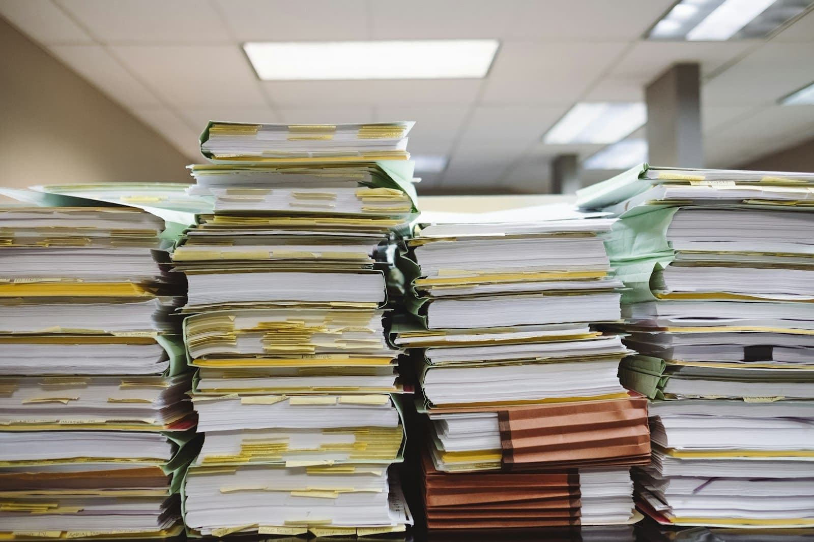 Tall stack of paper documents by an office window