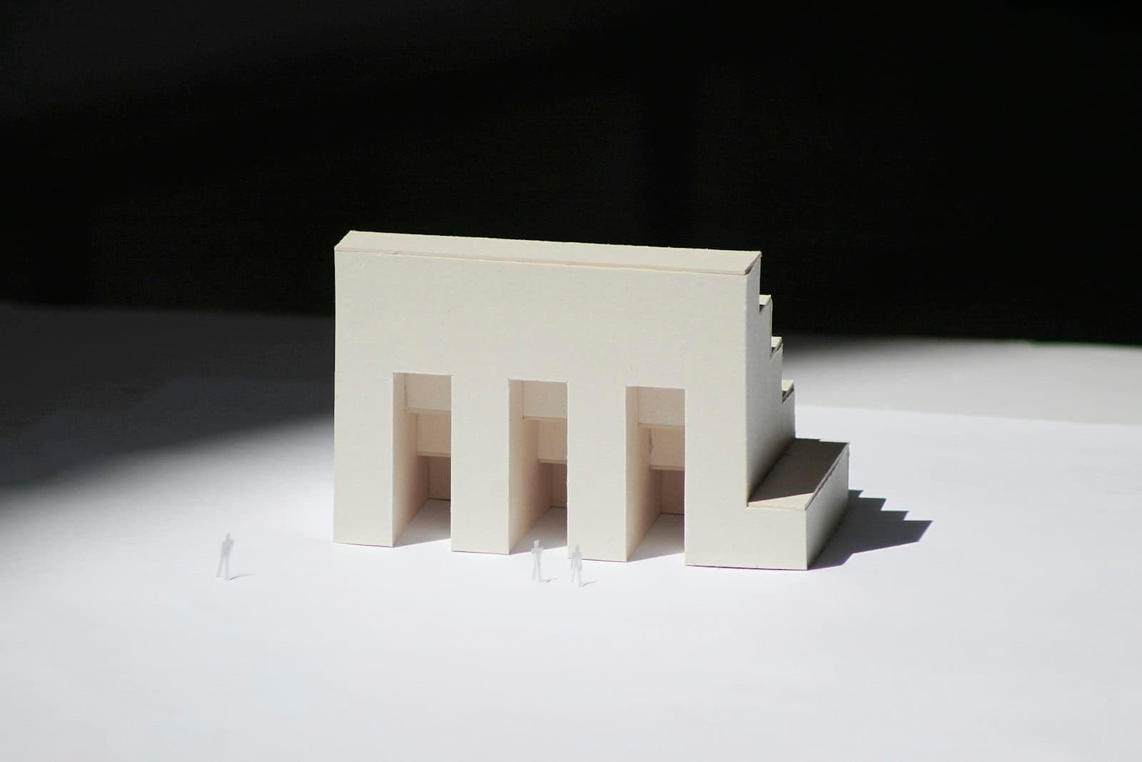 White architectural scale model lit against a dark background
